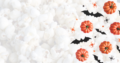 Halloween-themed decor with pumpkins, bats, and spiders on a popcorn background.