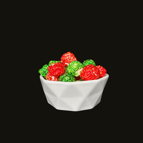 White bowl filled with red and green candied popcorn on a black background