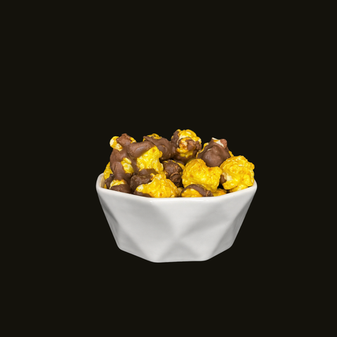 White bowl filled banana candied popcorn covered in chocolate on a black background