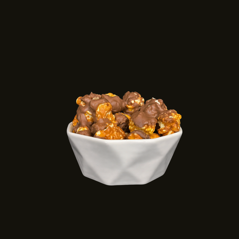 White bowl filled with chocolate candied and chocolate drizzled popcorn on a black background
