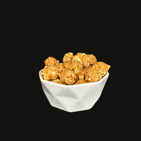 Bowl of peanut butter drizzled chocolate popcorn on a black background
